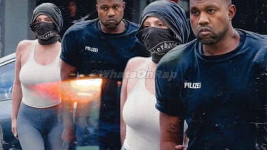 Kanye West wearing shoulder pads and blue socks, accompanied by Bianca Censori.